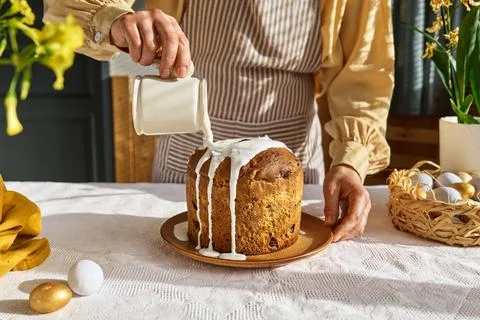 Female hands pouring icing on Easter cake. Traditional easter cake or sweet.. Stock Photos