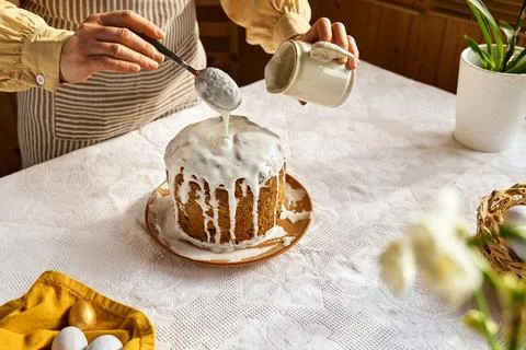 Female hands pouring icing on Easter cake. Traditional easter cake or sweet.. Stock Photos