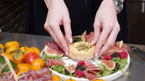 Female hands preparing a dish of baked cheese, prosciutto, berries and figs Stock Footage 145209585