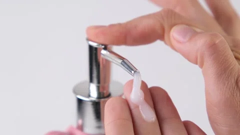 Female hands pressing the dispenser button and squeezing out liquid soap on a Stock Footage 321814495