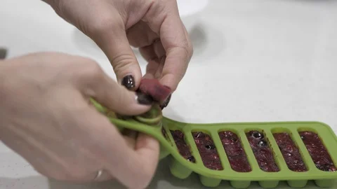 Female hands pull cubes from frozen berries from a green silicone mold. Stock Footage 126151435