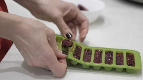 Female hands pull cubes from frozen berries from a green silicone mold. Stock Footage 126151623