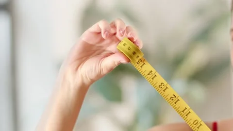 Female hands pull out a yellow measuring tape. A woman takes measurements with Stock Footage 239328006