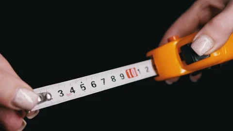 Female Hands Pulling Out Yellow Measuring Tape Against Black Background Stock Footage 338995935