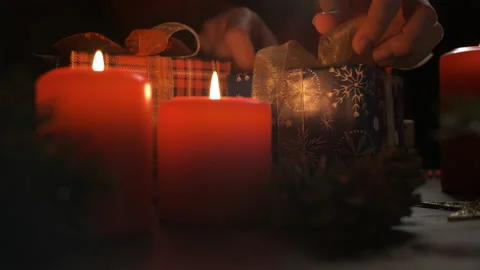 Female hands put and finalize Christmas gift on a table decorated Stock Footage 165345499