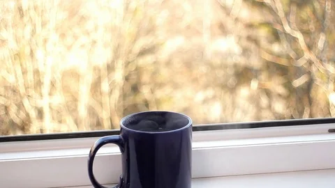 Female hands put a big blue cup with hot tea on the window sill Stock Footage 82582998