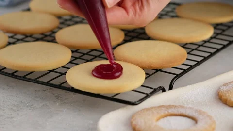 Female hands put jam on cookies from a pastry bag. Female hands a making Stock Footage 145363814