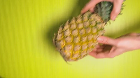 Female hands put pineapple on a bright yellow background. Minimal fruit concept. Stock Footage 100288357
