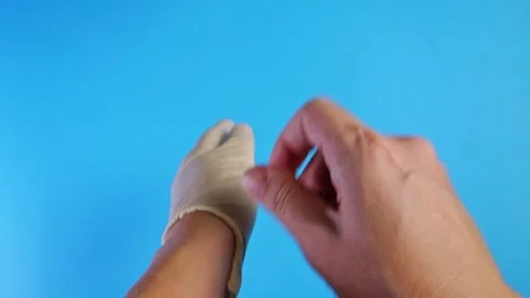 Female hands put on white rubber sterile gloves on a blue background. The doctor Stock Footage 147376783