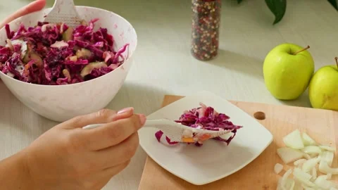 Female hands putting red cabbage salad with spoons on a white plate 스톡 동영상 297477565