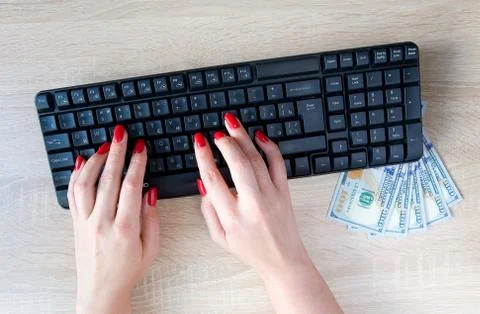 Female hands with red nails on a computer keyboard. Stock Photos