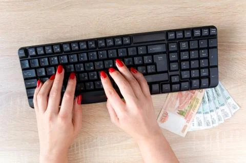 Female hands with red nails on a computer keyboard. Stock Photos