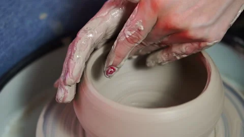 Female hands with red nails form gray clay bowl on a rotating potter's wheel Stock Footage 256325097