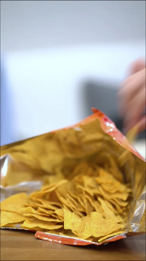 Female hands with red nails reaching into an open bag of golden nacho chips 스톡 동영상 342283479