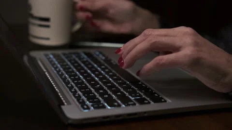 Female hands with red nails typing on the laptop keyboard and drinking coffee Видео 148249508