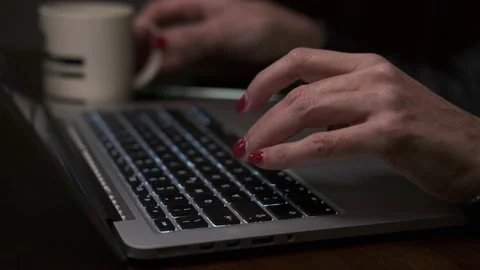 Female hands with red nails typing on the laptop keyboard and drinking coffee Stock Footage 148264780