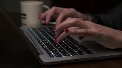 Female hands with red nails typing on laptop keyboard, side view. Видео 148271941