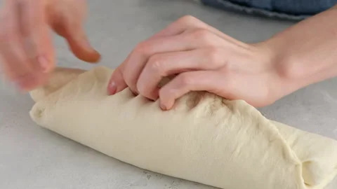 Female hands roll the dough into a roll on a light table for making wheat bread Stock Footage 146141223