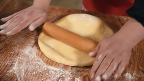 Female hands roll out dough with a rolling pin in the kitchen, close-up. Dough Stock Footage 253744204