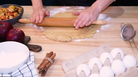Female hands rolling a dough with rolling pin on the table close-up. Stock Footage 121881401