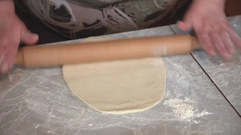 Female hands rolling out dough with a rolling pin on a light table. Stock Footage 74994120