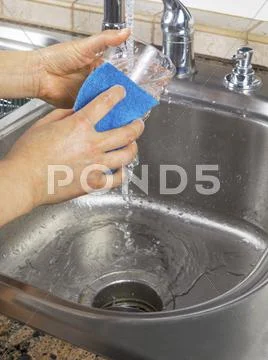 Female hands running water into soapy drinking glass Stock Photos