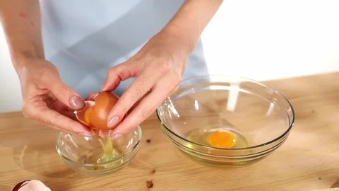 Female hands separate the egg yolk from the protein. Close-up. Stock Footage 245261548