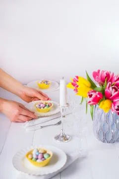 Female hands serving Easter table with colorful sweet eggs in cases on the pl Stock Photos