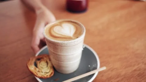 Female hands serving white cup with heart shape coffee in slow motion. Stock Footage 179884715