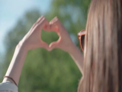 Female hands in shape of heart over green nature and blue sky. 動画素材 79643256