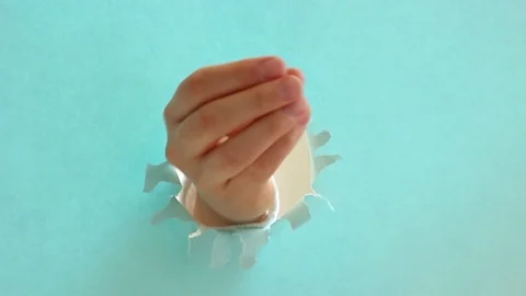 Female hands in the shape of a heart on torn blue paper background. Stock Footage 124521898