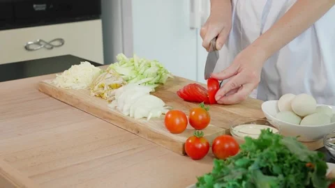 Female hands with a sharp knife cut a tomato into slices preparing a frittata Stock Footage 270151385