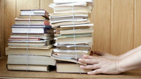 Female hands on the shelf shift the stack of books and put the tablet Stock Footage 114292720