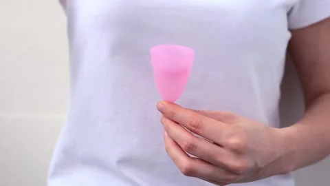 Female hands show using menstrual cup with red feather. Woman hand holding Stock Footage 167322135