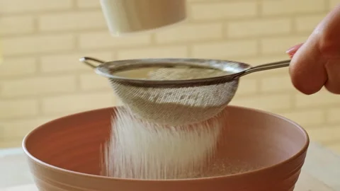 Female hands sifting flour into a bowl to prepare dough Stock Footage 280856490