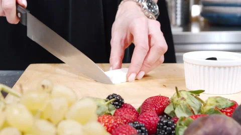 Female hands slicing cheese preparing appetizer of feta cheese and fresh berries Stock Footage 145204280