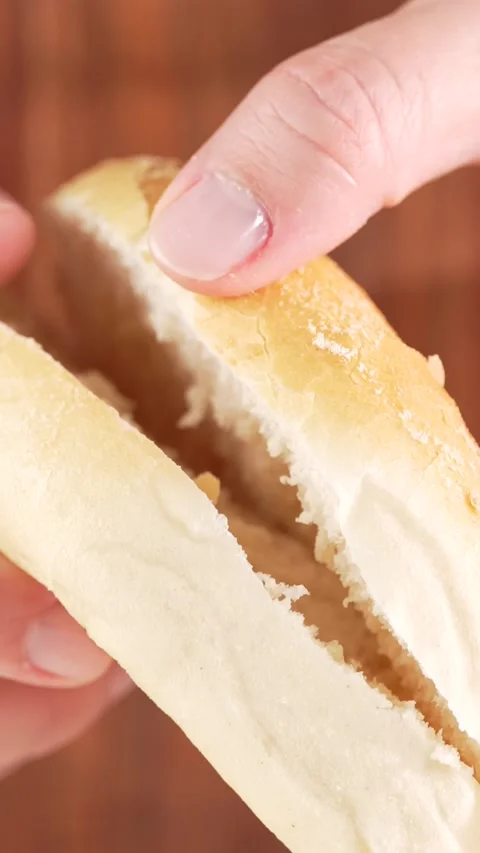 Female Hands Splitting Soft Bun in Half on Wooden Blurred Background  Verti.. Stock Footage 312169244