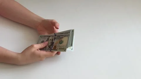 Female hands spreading stack of one hundred dollar bills across white Stock Footage 345170589
