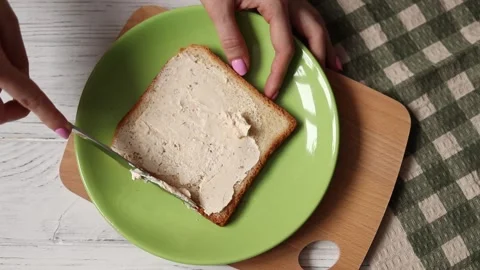 Female hands spreading white bread toast with soft cream cheese, top view Stock Footage 150361177