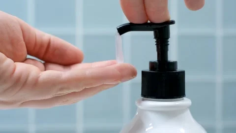 Female hands squeeze soap with dispenser close up against background of blue Stock Footage 306561459