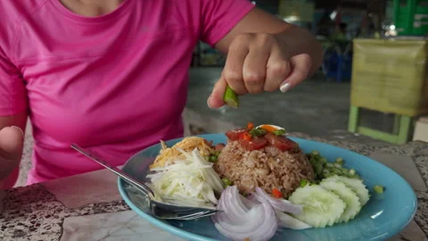 Female hands squeezing lime over Asian rice dish in local restaurant food Видео 331555140