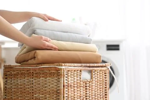 Female hands with stack of clean bed sheets on basket in laundry room Stock Photos