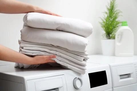 Female hands with stack of clean bed sheets in bathroom Stock Photos