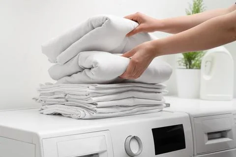 Female hands with stack of clean bed sheets in bathroom Stock Photos