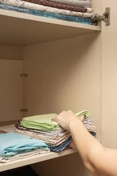 Female hands stack folded linen in closet Foto stock