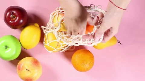 Female hands stack fruits in a string bag Stock Footage 132955463