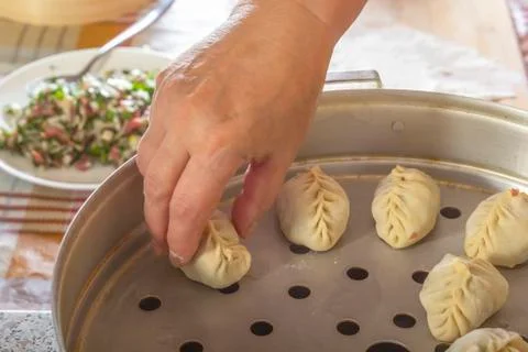 Female hands stack raw manti, dumplings or wonton from dough with minced meat Stock Photos
