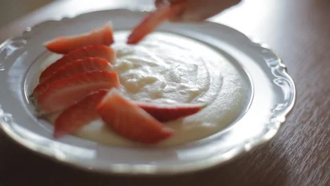 Female hands stack strawberry slices in a plate with semolina. Healthy food. Video stock 106268282