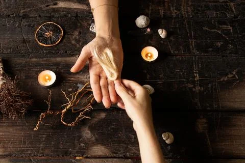 Female hands surrounded by shells and candles, roots, strands of hair and m.. Stock-Fotos