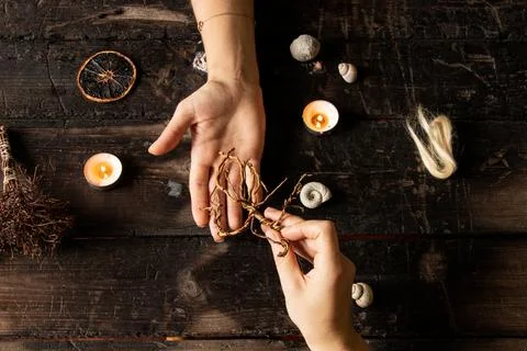 Female hands surrounded by shells and candles, roots, strands of hair and mag Stock Photos
